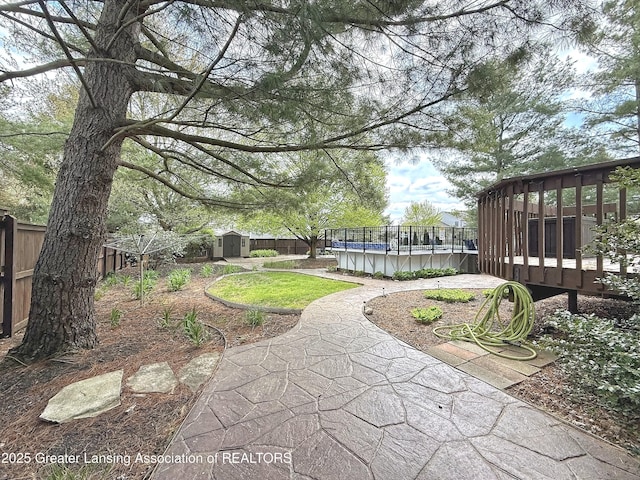 1970 Hollowbrook Dr, Holt, MI 48842 - view of yard featuring a storage shed, a wooden deck, a fenced in pool, an outdoor structure, and a fenced backyard