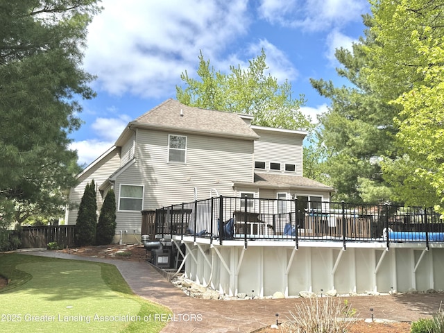 1970 Hollowbrook Dr, Holt, MI 48842 - back of property with fence, a wooden deck, roof with shingles, and a fenced in pool
