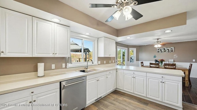 kitchen with dishwasher, a sink, a ceiling fan, a peninsula, and light wood finished floors
