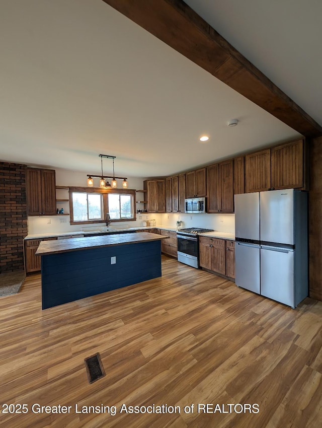 kitchen featuring visible vents, open shelves, stainless steel appliances, light wood-style flooring, and a kitchen island
