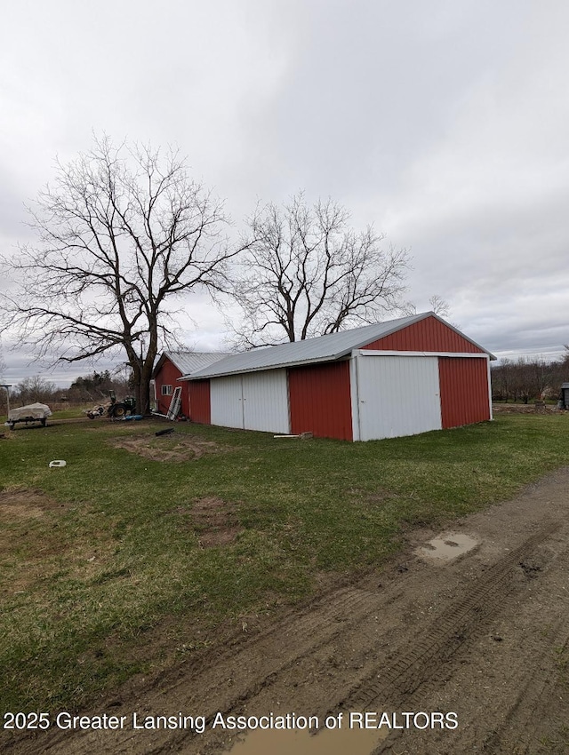 view of pole building with driveway and a lawn