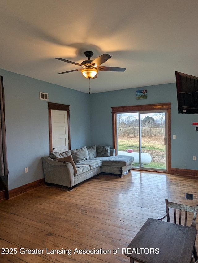living area with visible vents, ceiling fan, hardwood / wood-style floors, and baseboards