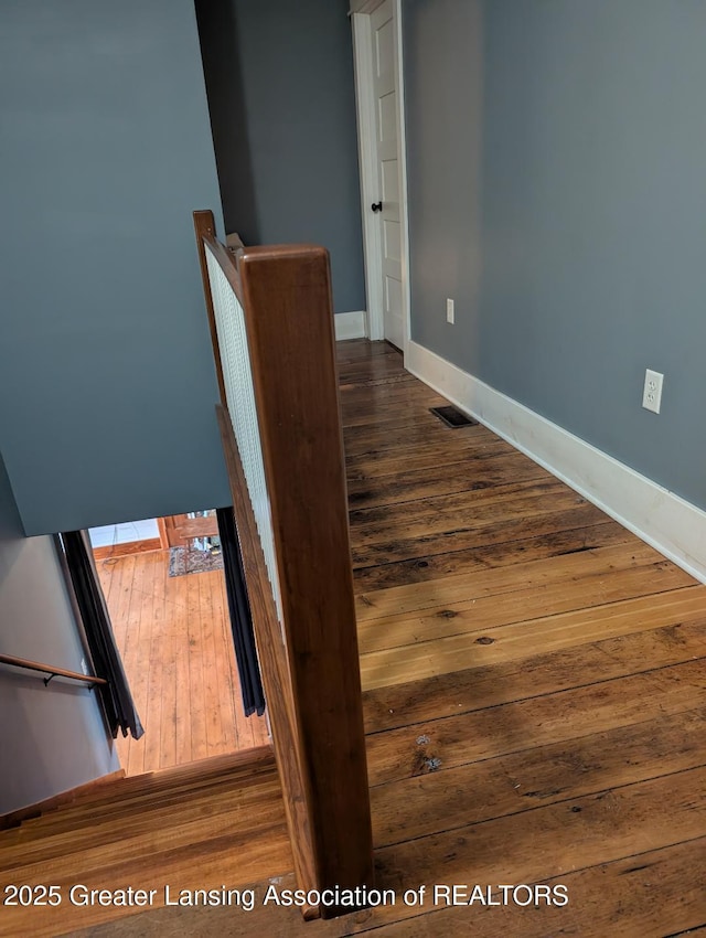 stairway with visible vents, baseboards, and hardwood / wood-style floors