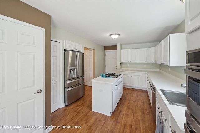14178 Mulholland Dr, Bath, MI 48808 - kitchen featuring a center island, wood finished floors, light countertops, white cabinets, and appliances with stainless steel finishes
