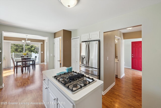 14178 Mulholland Dr, Bath, MI 48808 - kitchen with white cabinets, stainless steel appliances, light wood finished floors, an inviting chandelier, and light countertops