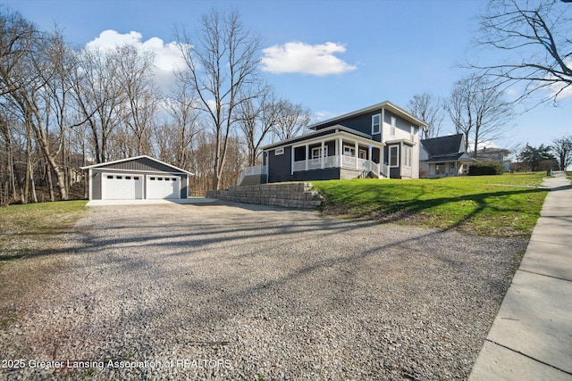 view of front of house with an outbuilding, covered porch, a detached garage, and a front lawn