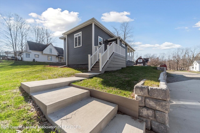 view of side of home with stairway and a lawn