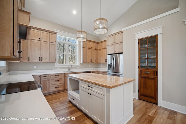 kitchen featuring stainless steel fridge with ice dispenser, vaulted ceiling, a sink, wood counters, and light wood finished floors