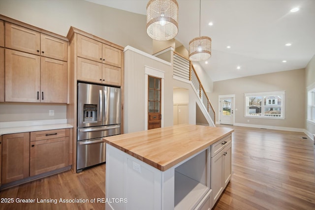 kitchen with open floor plan, light wood-type flooring, wood counters, and stainless steel refrigerator with ice dispenser