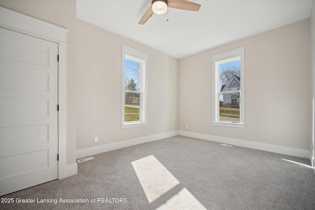carpeted empty room featuring visible vents, baseboards, and a ceiling fan