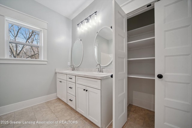 bathroom with tile patterned floors, double vanity, a sink, and baseboards