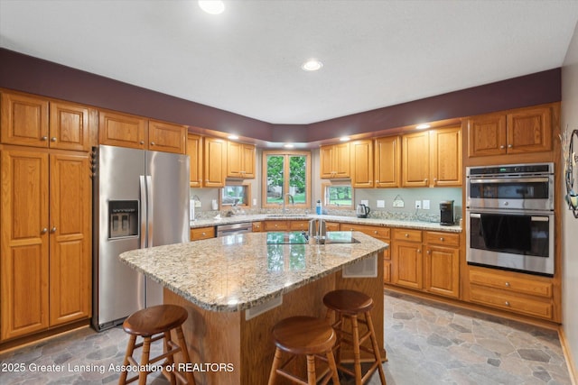 5810 Caleta Dr, Lansing, MI 48911 - kitchen featuring stainless steel appliances, light stone finish flooring, a breakfast bar area, light stone countertops, and recessed lighting
