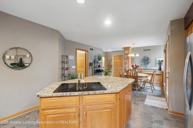 5810 Caleta Dr, Lansing, MI 48911 - kitchen featuring dark stone finish floors, black electric cooktop, a kitchen island, light stone countertops, and baseboards