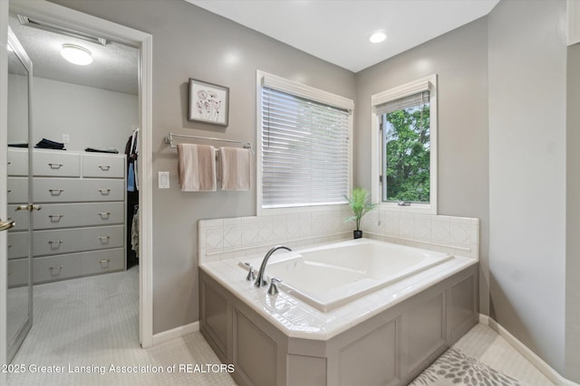 5810 Caleta Dr, Lansing, MI 48911 - bathroom featuring baseboards, a walk in closet, a garden tub, and tile patterned floors
