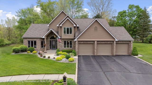 5810 Caleta Dr, Lansing, MI 48911 - view of front of house with an attached garage, asphalt driveway, brick siding, a front lawn, and roof with shingles