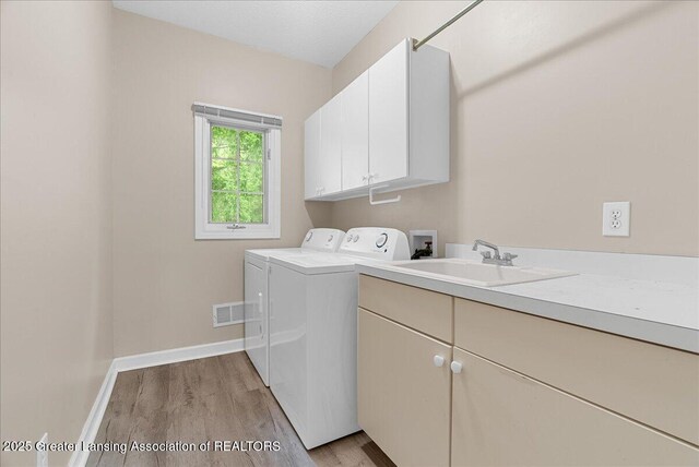 4345 Courtside Dr, Williamston, MI 48895 - clothes washing area with cabinet space, separate washer and dryer, light wood-style flooring, and baseboards