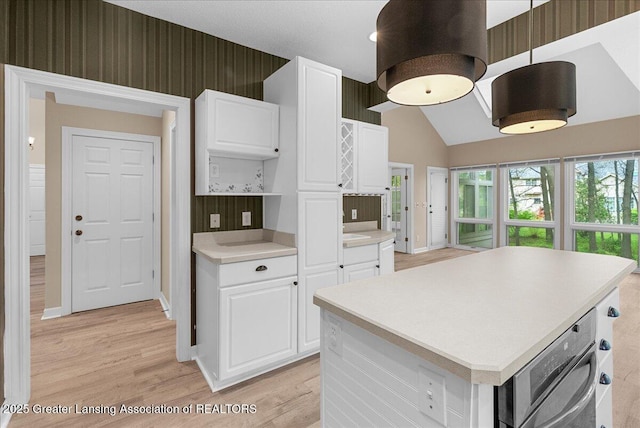 4345 Courtside Dr, Williamston, MI 48895 - kitchen with light wood finished floors, light countertops, white cabinetry, a center island, and lofted ceiling