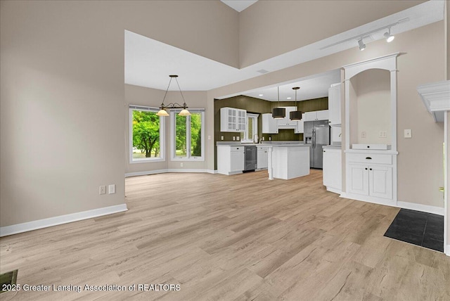 4345 Courtside Dr, Williamston, MI 48895 - unfurnished living room featuring light wood-style flooring, baseboards, and track lighting