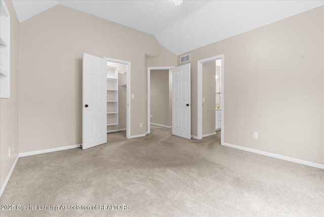 4345 Courtside Dr, Williamston, MI 48895 - unfurnished bedroom featuring vaulted ceiling, carpet flooring, a walk in closet, baseboards, and connected bathroom