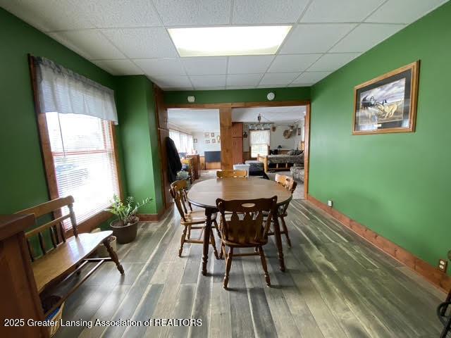 dining space with baseboards, a paneled ceiling, and wood finished floors