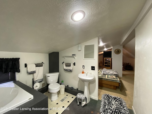 bathroom with a bath, toilet, a textured ceiling, and lofted ceiling