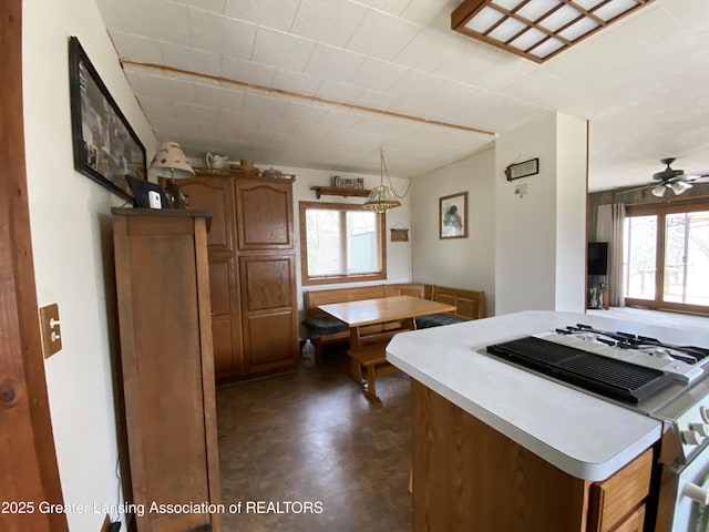 kitchen featuring brown cabinets, a healthy amount of sunlight, light countertops, and stove
