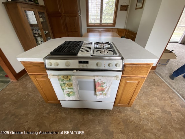 kitchen featuring brown cabinets, light countertops, and white range with gas cooktop