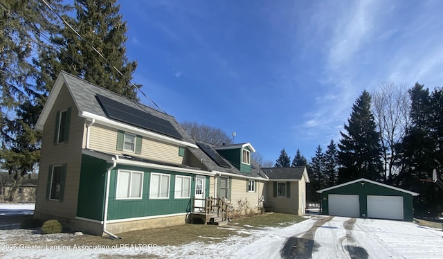 colonial inspired home featuring an outbuilding, a detached garage, and roof mounted solar panels