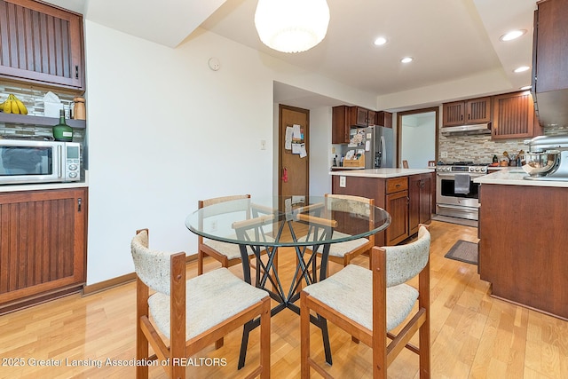 1210 Whittier Dr, East Lansing, MI 48823 - kitchen featuring light countertops, light wood-style flooring, stainless steel appliances, backsplash, and a kitchen island