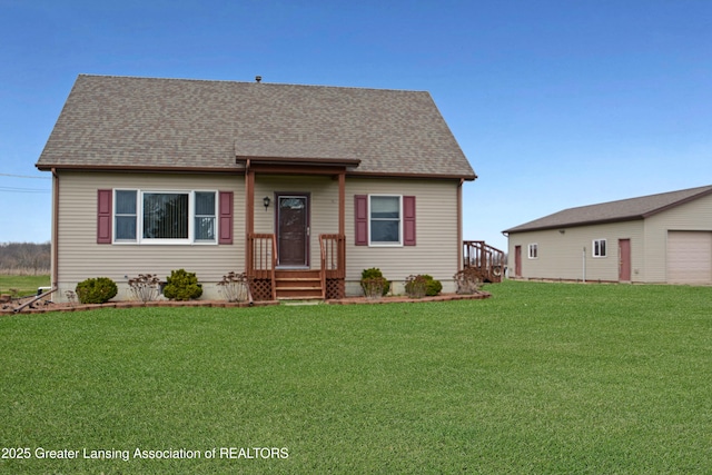 view of front of home with a garage, a front yard, an outdoor structure, and a shingled roof