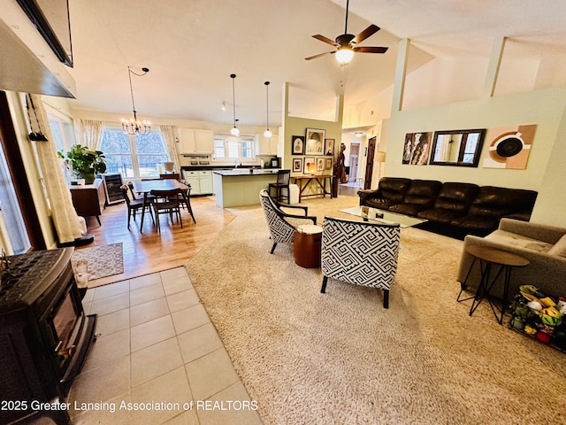 living room featuring ceiling fan with notable chandelier, light tile patterned floors, and high vaulted ceiling