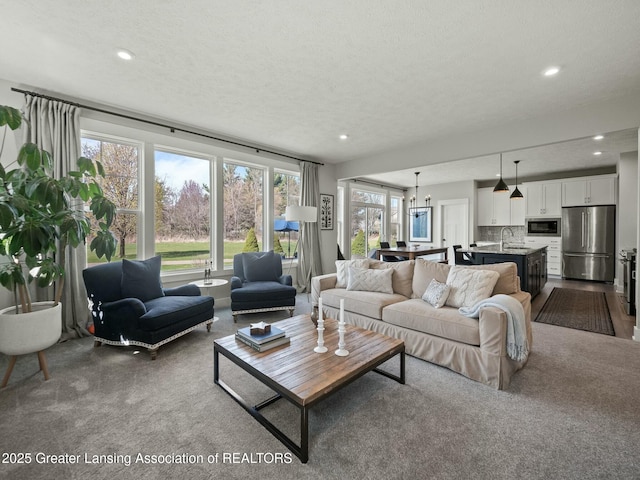 living room with recessed lighting, dark colored carpet, and a textured ceiling