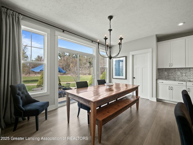 dining area featuring dark wood finished floors, a textured ceiling, and an inviting chandelier