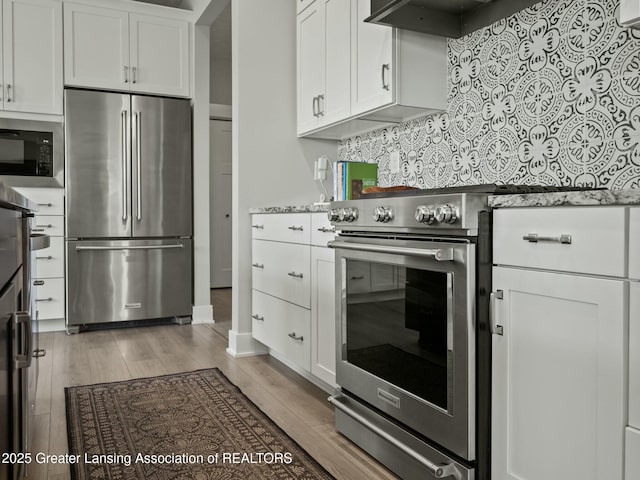 kitchen featuring white cabinets, light wood-type flooring, appliances with stainless steel finishes, and range hood