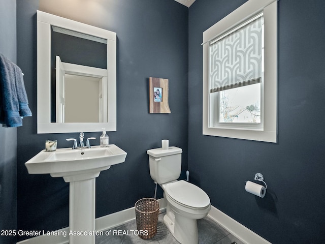 half bathroom with tile patterned floors, baseboards, and toilet