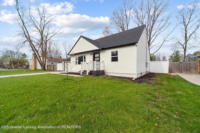 view of front of home featuring roof with shingles, a front lawn, and fence