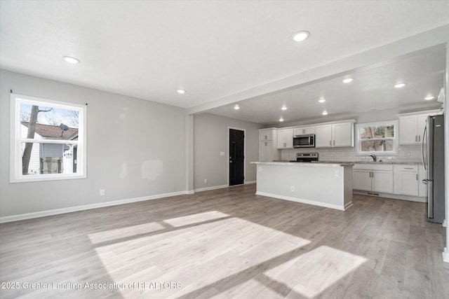 kitchen with light wood finished floors, plenty of natural light, appliances with stainless steel finishes, and a center island