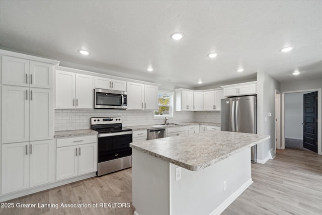 kitchen with light countertops, light wood finished floors, appliances with stainless steel finishes, and a sink