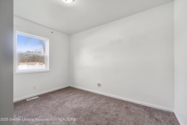 spare room featuring baseboards, visible vents, and carpet