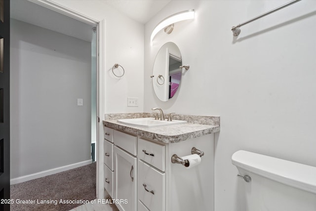 bathroom featuring baseboards, vanity, and toilet