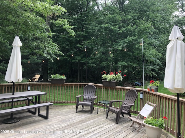 wooden deck featuring outdoor dining area and a lawn