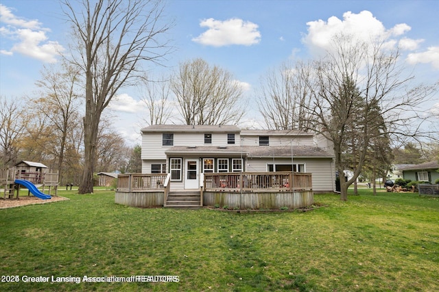back of property with a shingled roof, a wooden deck, a playground, and a lawn