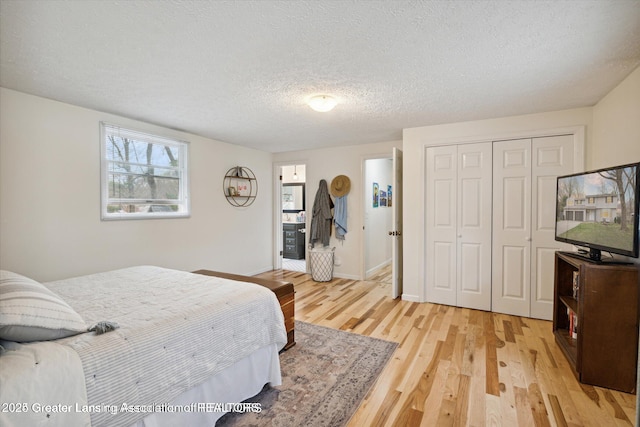 bedroom with a closet, baseboards, light wood-style floors, and a textured ceiling