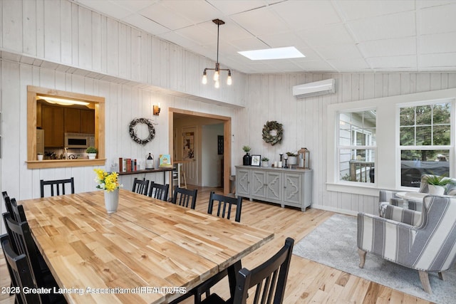 dining area with wood walls, wood finished floors, and a wall unit AC