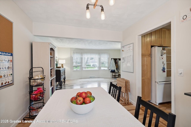 dining room featuring baseboards and light wood-type flooring