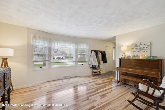 sitting room featuring visible vents, a textured ceiling, baseboards, and wood finished floors