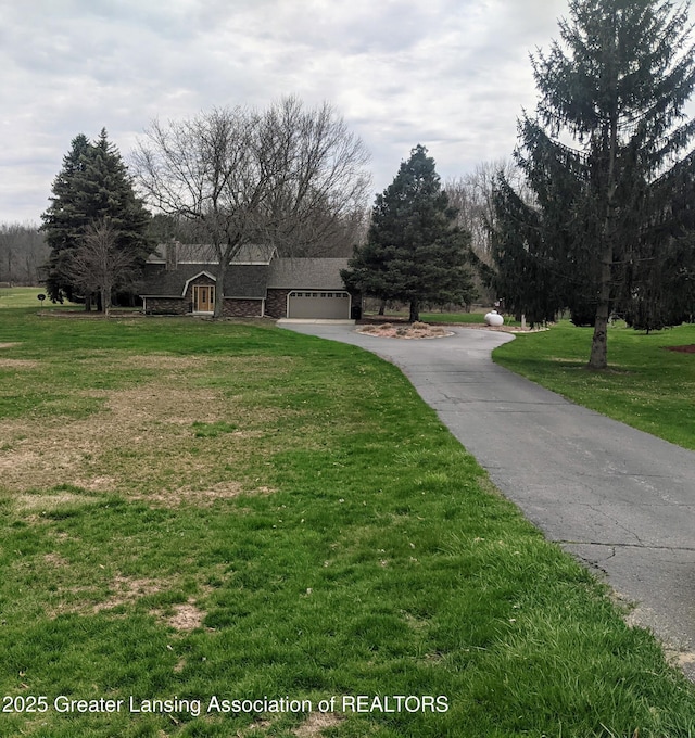 exterior space featuring aphalt driveway, an attached garage, and a front yard