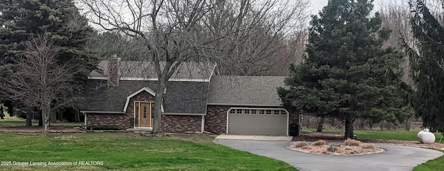 view of front of house featuring a shingled roof, aphalt driveway, a front yard, and a garage