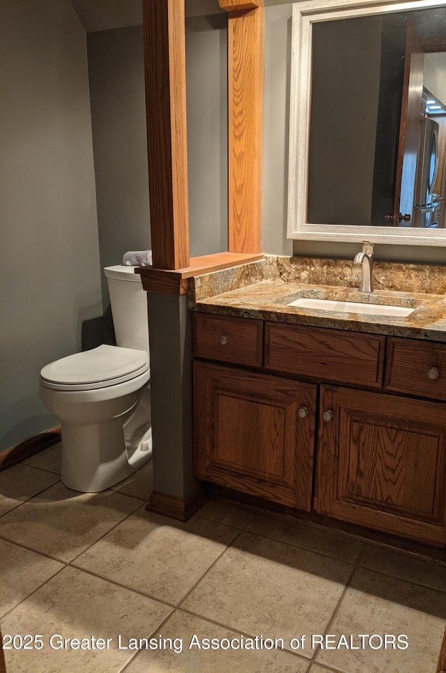 half bathroom featuring toilet, vanity, baseboards, and tile patterned flooring
