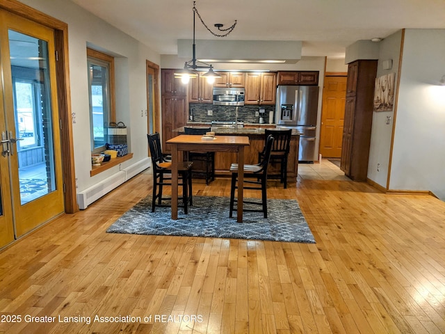 dining room featuring light wood-style floors, a baseboard heating unit, and baseboards